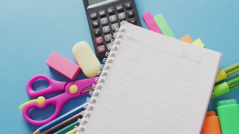 video of school supplies, notebook, pens, marker pen over blue background