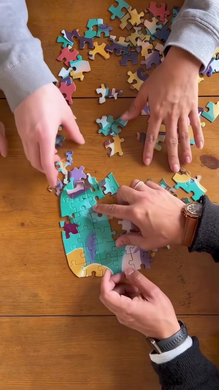 Grupo de personas armando un colorido rompecabezas sobre una mesa de madera