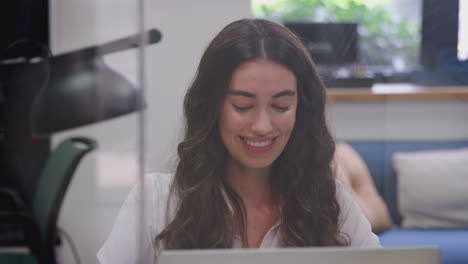 mujer de negocios sentada en un escritorio en una oficina moderna trabajando en una computadora portátil hablando por teléfono