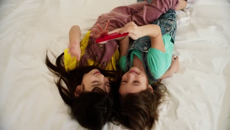 two cute smiling preshool girls watching cartoons on smartphone