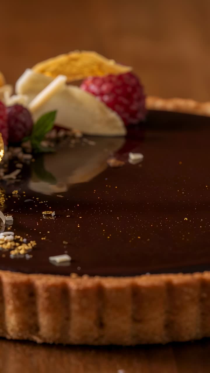 Vertical video: Sliding camera showing glossy chocolate tart on wood table, highlighting texture