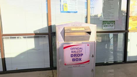 millennial woman votes by droping mail-in ballot letter in slot at voting booth with offical ballot drop box sign for democratic government election in presidential race