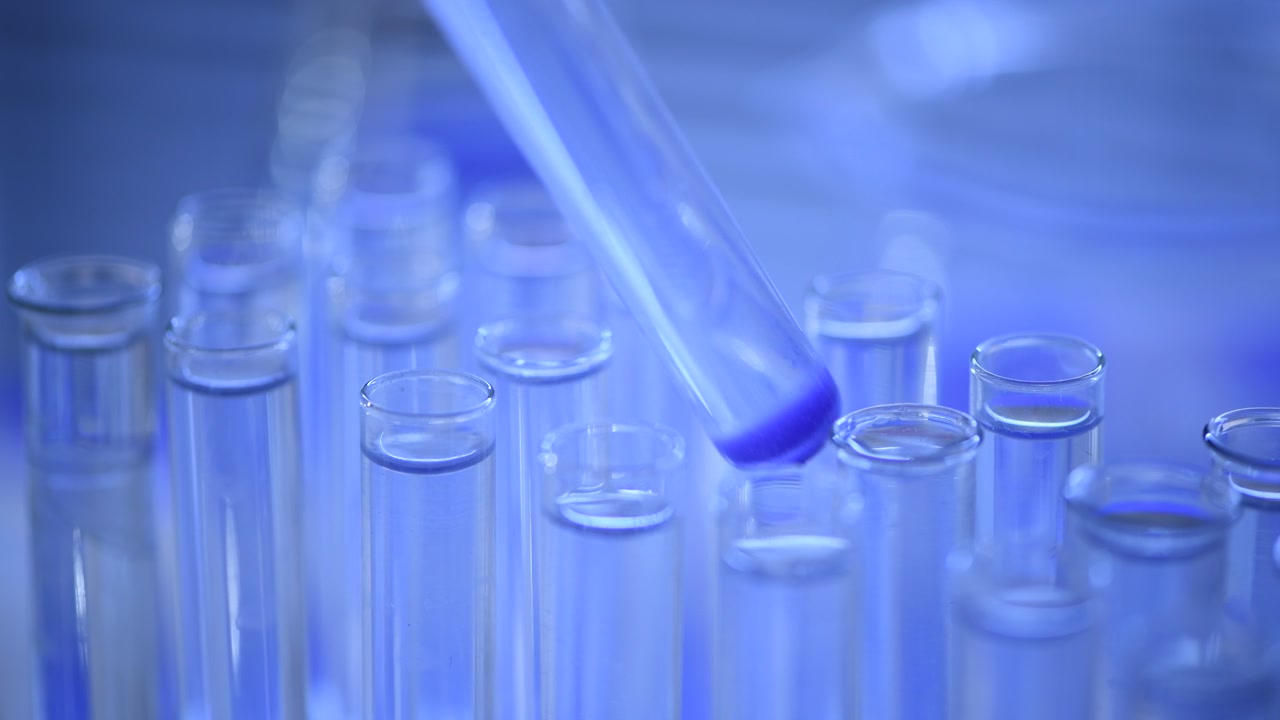 Mano di scienziato che pipetta liquido viola in provetta in laboratorio