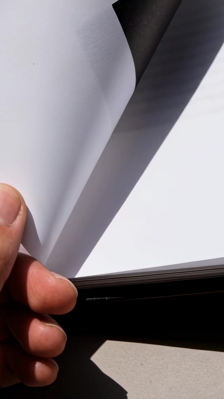 Vertical video: Entering hand peeling sheet corner to separate sheet from pad on table, copy space