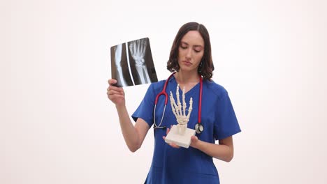 female medical professional examining hand x-ray with skeletal model