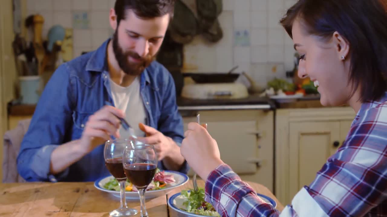 pareja de jóvenes hablando mientras comen en la cocina