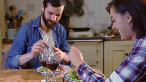 Pareja-Joven-Hablando-Mientras-Come-En-La-Cocina