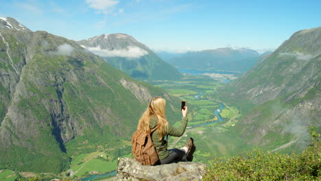 mujer tomando una foto del pintoresco paisaje de los fiordos noruegos