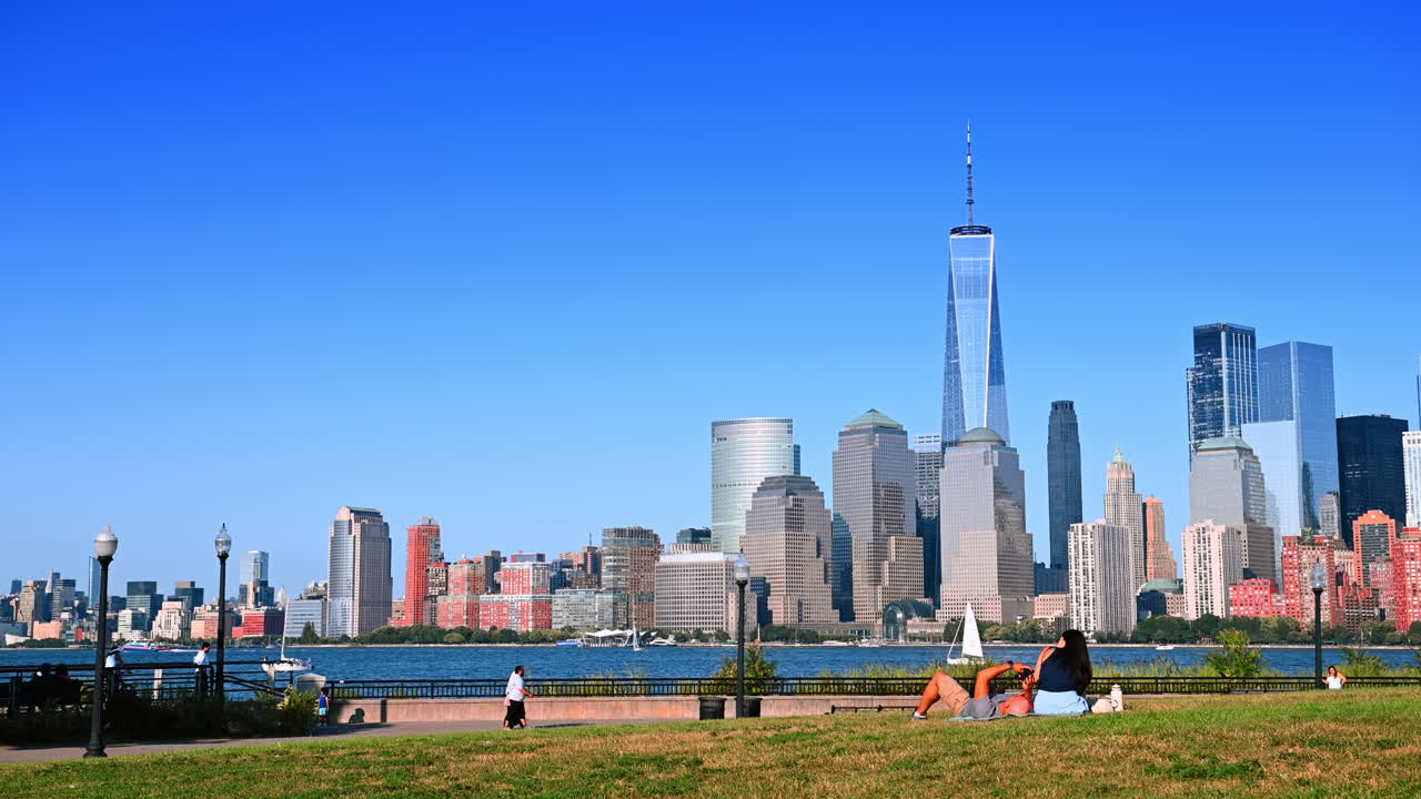 Jersey City, USA, 1. juli 2025: Par slapper af på græsset med Manhattan skyline på den anden side af Hudsonfloden. Et par slapper af på græsset i en park i Jersey City med Manhattan skyline på den anden side af Hudsonfloden