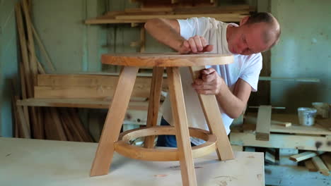 a craftsman assembles a wooden stool in a workshop