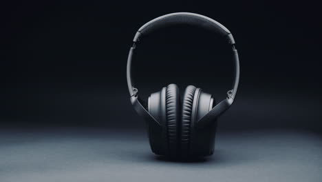 a product shot of black headphones on a black background, standing upright