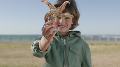 portrait of cute cheerful boy smiling happy at camera holding starfish enjoying sunny day on seaside  beach park