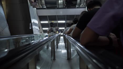 crowded passengers on singapore mrt station escalator during rush hour.
