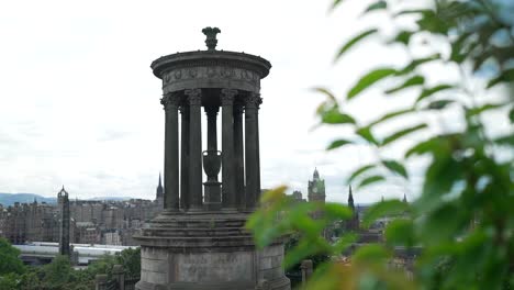 Handheld-slider-past-blades-of-grass-reveals-dugald-tower-in-Edinburgh