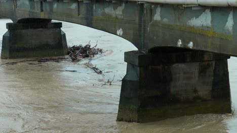 Intense-footage-capturing-the-impact-of-a-cyclone-as-wood-debris-collects-under-a-bridge,-showcasing-the-raw-force-and-aftermath-of-nature's-fury