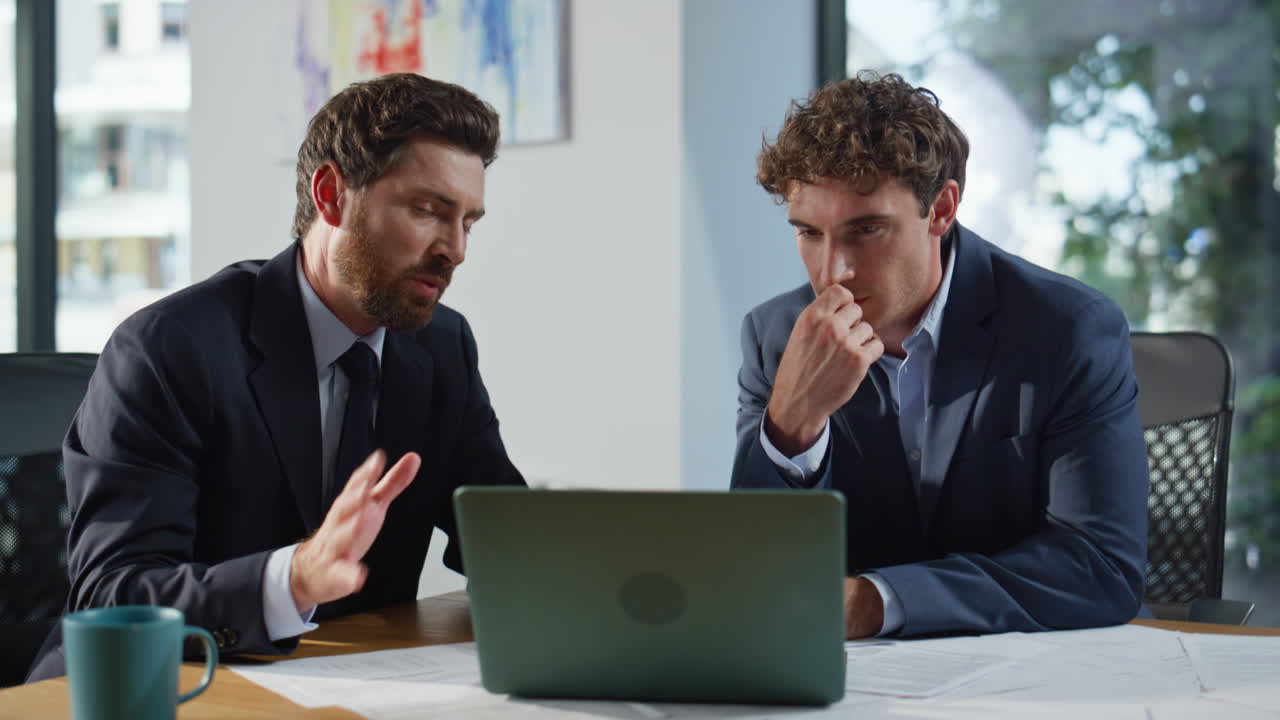 Business partners discussing project at laptop sitting corporate office closeup