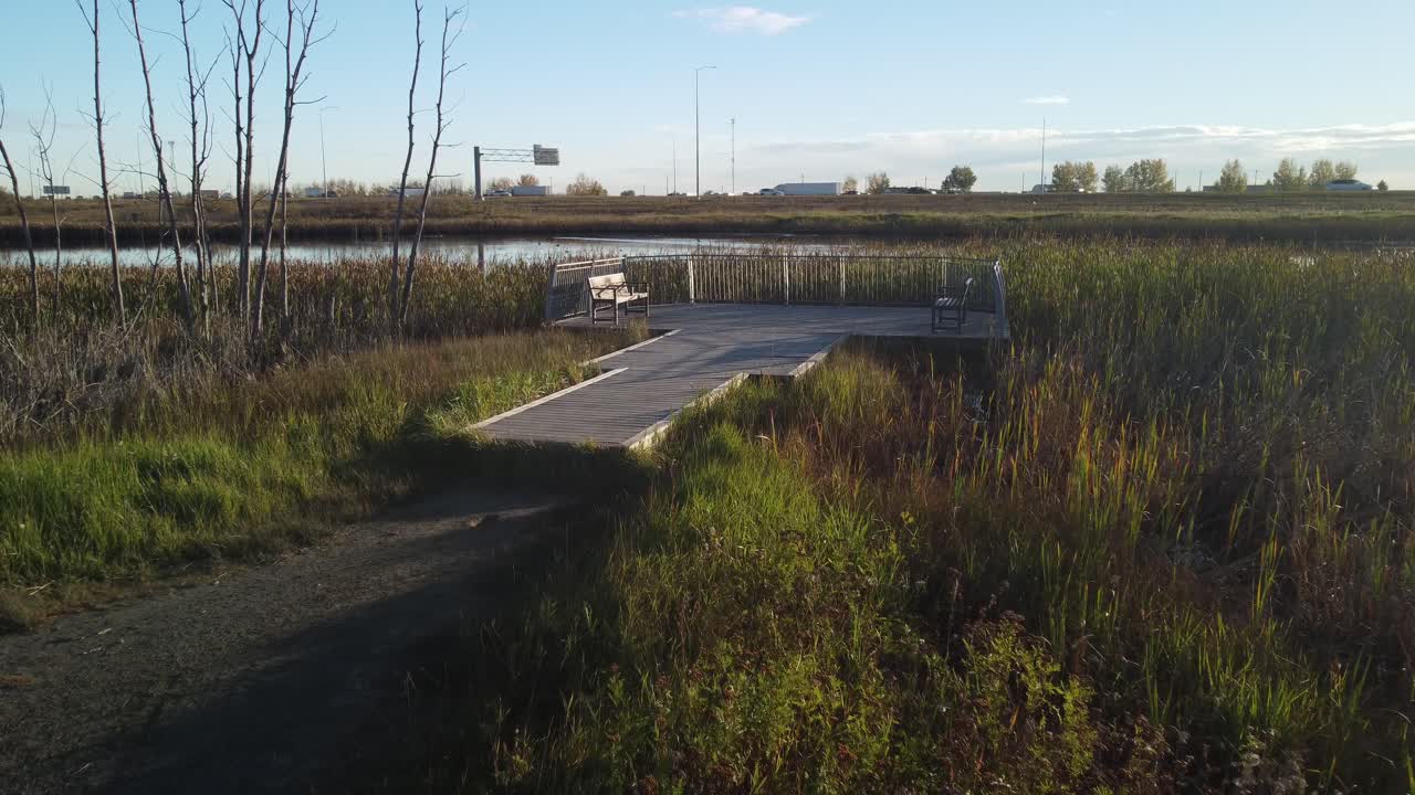 Empty benches by pond and highway on deck