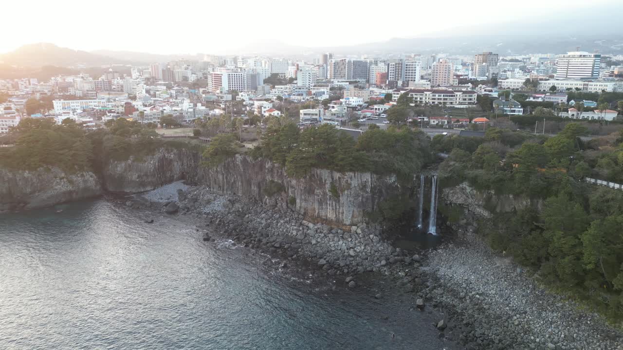 Drone aerial view in South Korea near a cliff with green trees over rocky area city background jeju island