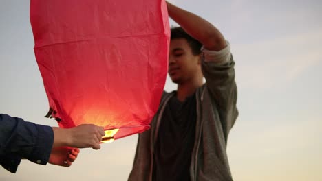 close up view of young multi ethnic couple holding red paper lantern before launching. attractive woman with her african boyfriend