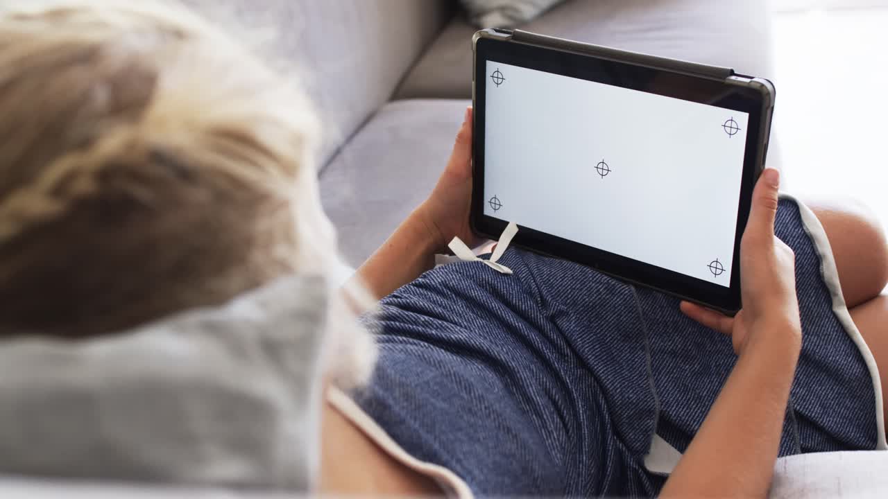 Teenage female reclining on sofa in shorts, adjusting tablet grip after seeing calibration marks