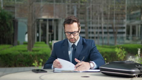 Businessman-writing-notes-in-documents-outdoors-in-a-park---orbit-shot