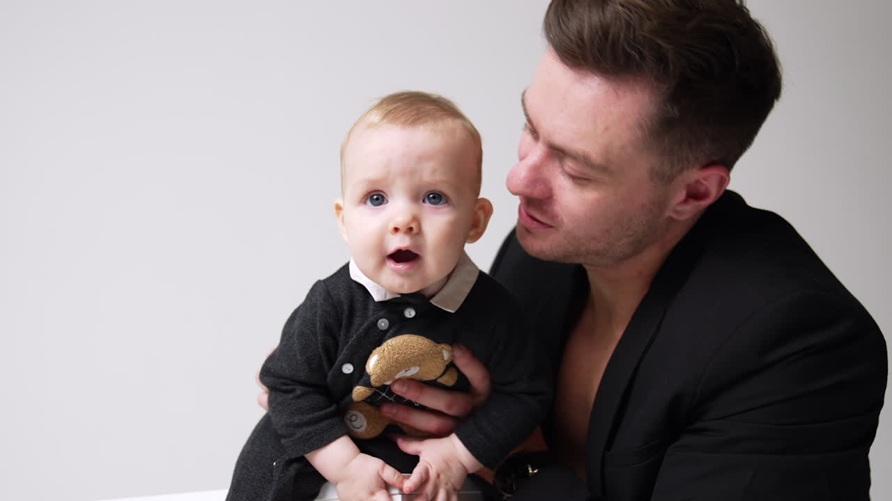 Father is holding a baby and kissing him on the head. Father and son together. Close up.