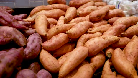 a vibrant assortment of sweet potatoes arranged in a supermarket setting, showcasing diverse colors and textures under bright lighting