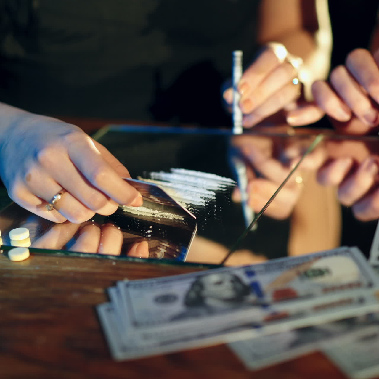 Preparing cocaine for snorting. Two young girls snorting an illegal white powder with rolled up dollar bills.