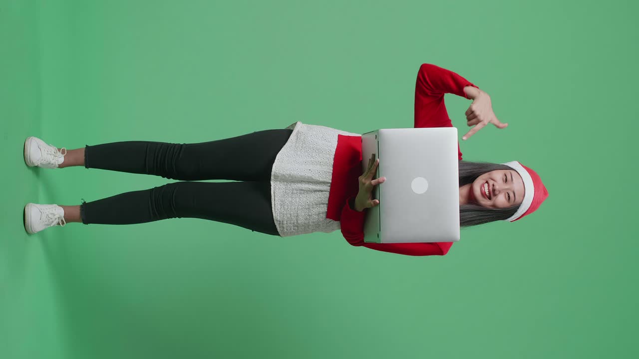 mujer con sombrero de santa con una computadora portátil