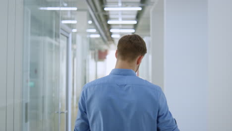 Unknown-man-walking-through-glass-wall-space.-Businessman-looking-around-office