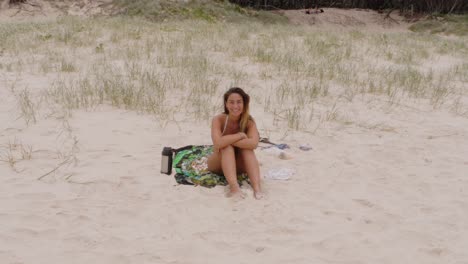 chica guapa sonriendo sentada en las arenas blancas de la playa principal, mirador en north stradbroke island, queensland, australia