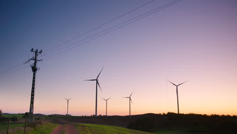 Dramatic-sunset-silhouette-of-wind-turbines-and-power-lines,-wide