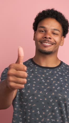 happy man showing thumbs up in pink studio