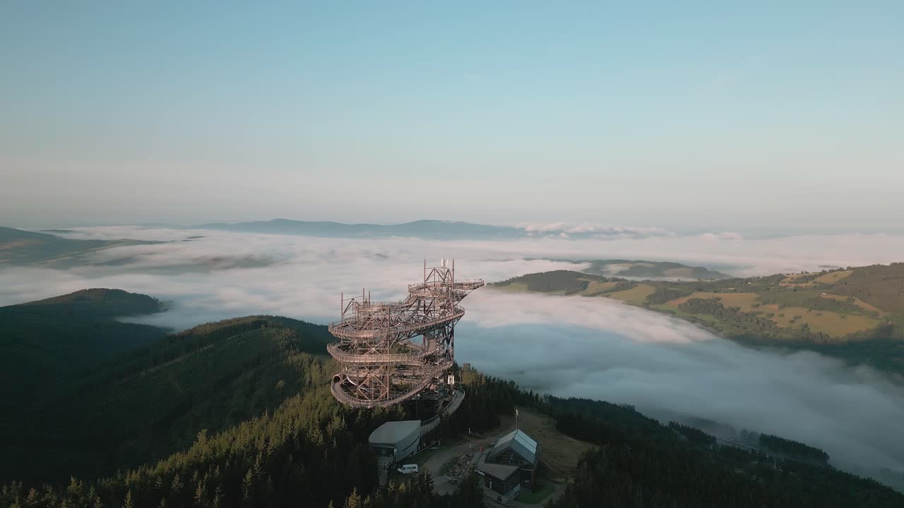 A flight around a lookout towering over a misty valley.