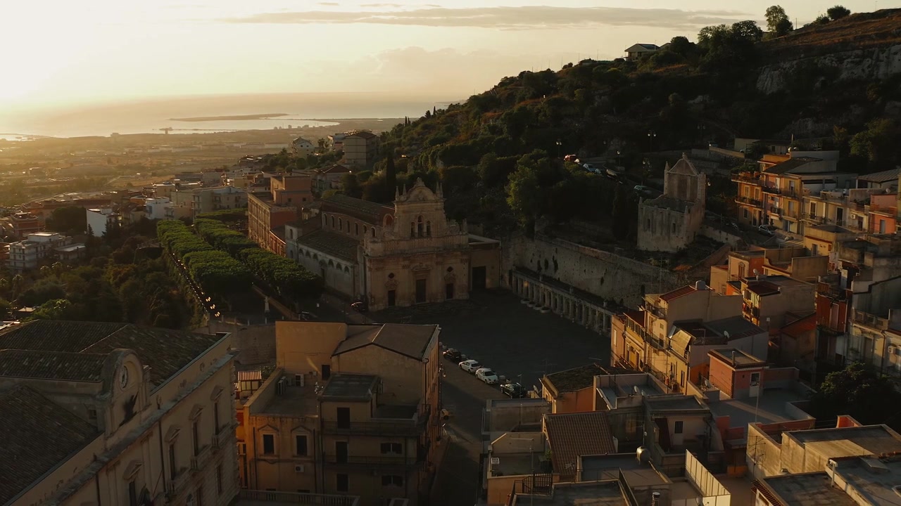 Sorvolo mozzafiato con drone all'alba del borgo storico collinare di Melilli in Sicilia, Italia.