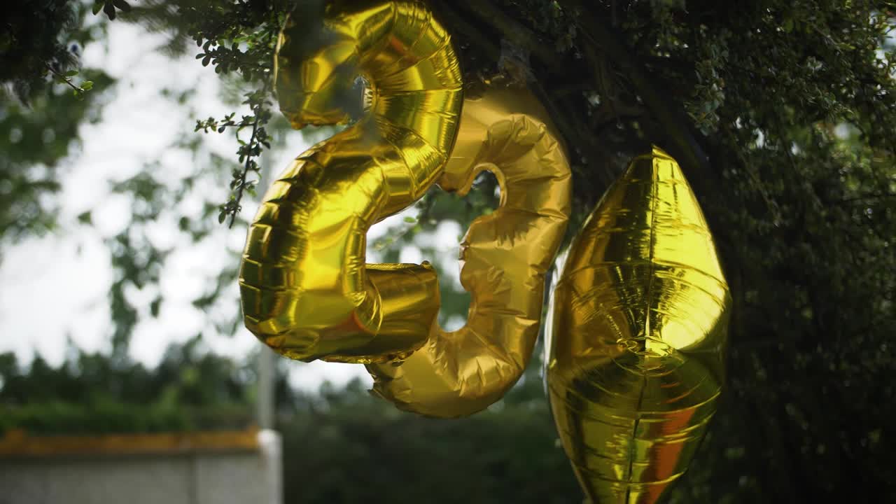 23 globos de cumpleaños dorados colgados en la fiesta de verano en el jardín