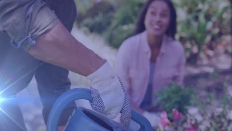 animación de luces brillantes sobre una feliz pareja biracial regando plantas en el jardín