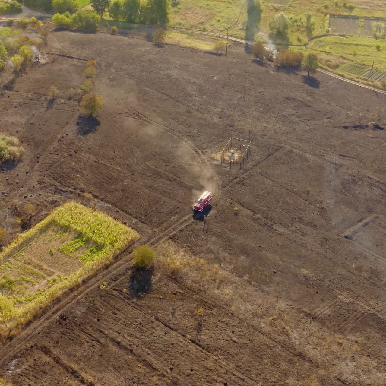 Fire truck moving on burnt field. Brown field after the fire in summer. Environment in danger. Natural environment in smoke after the fire accident. Aerial view.