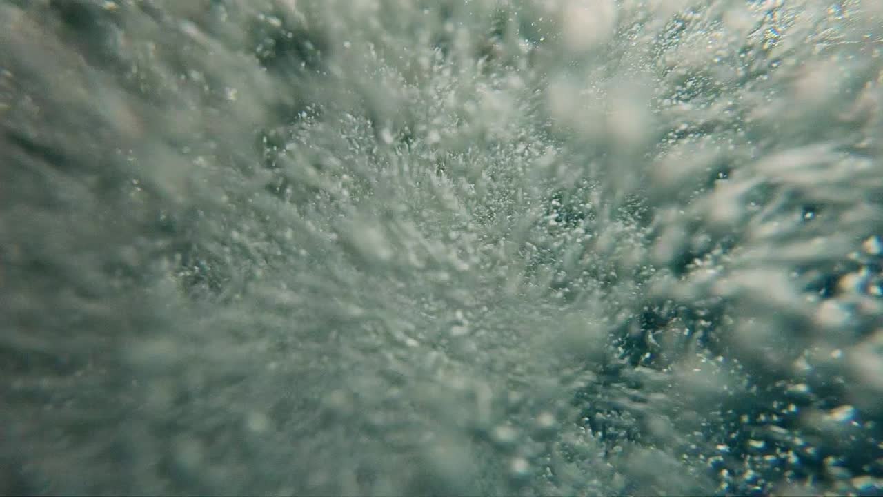 Аir bubbles floating from the bottom to the surface of the water, slow motion