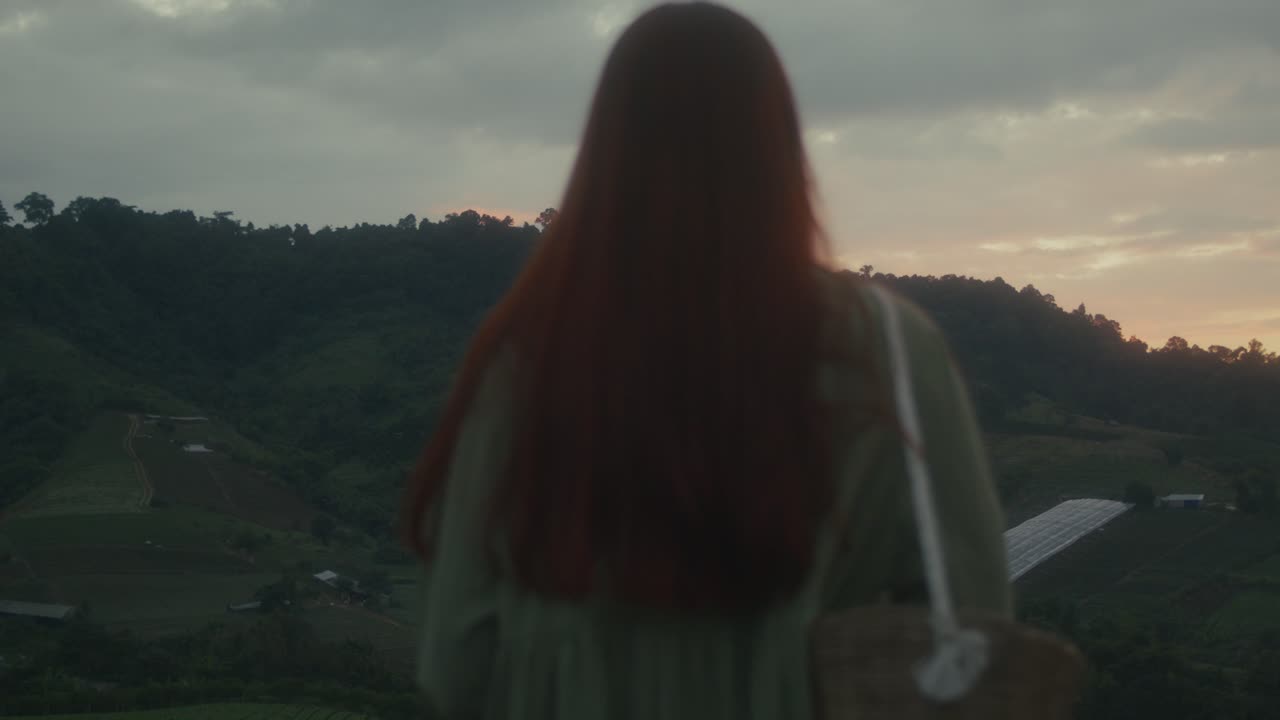 Woman watching sunset over mountains
