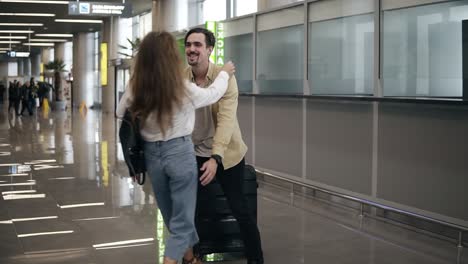 Bearded-young-man-with-suitcase,-waiting-for-his-girlfriend,-in-airport-flying-back-home-from-business-trip-after-long