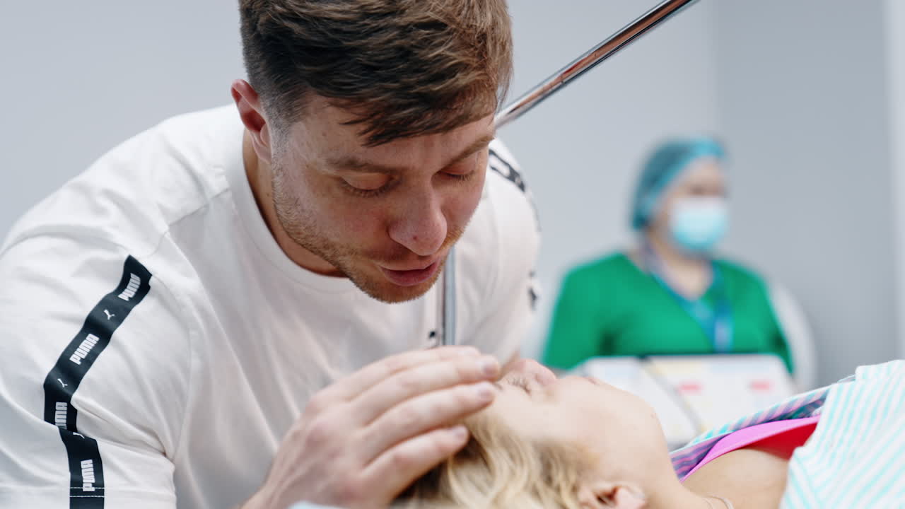 Bearded man comforting his wife before the C-section surgery. Husband strokes woman's head soothing her. Close up.