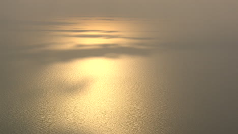 setting sun reflects on the sea with some patches of shadow casted by the clouds