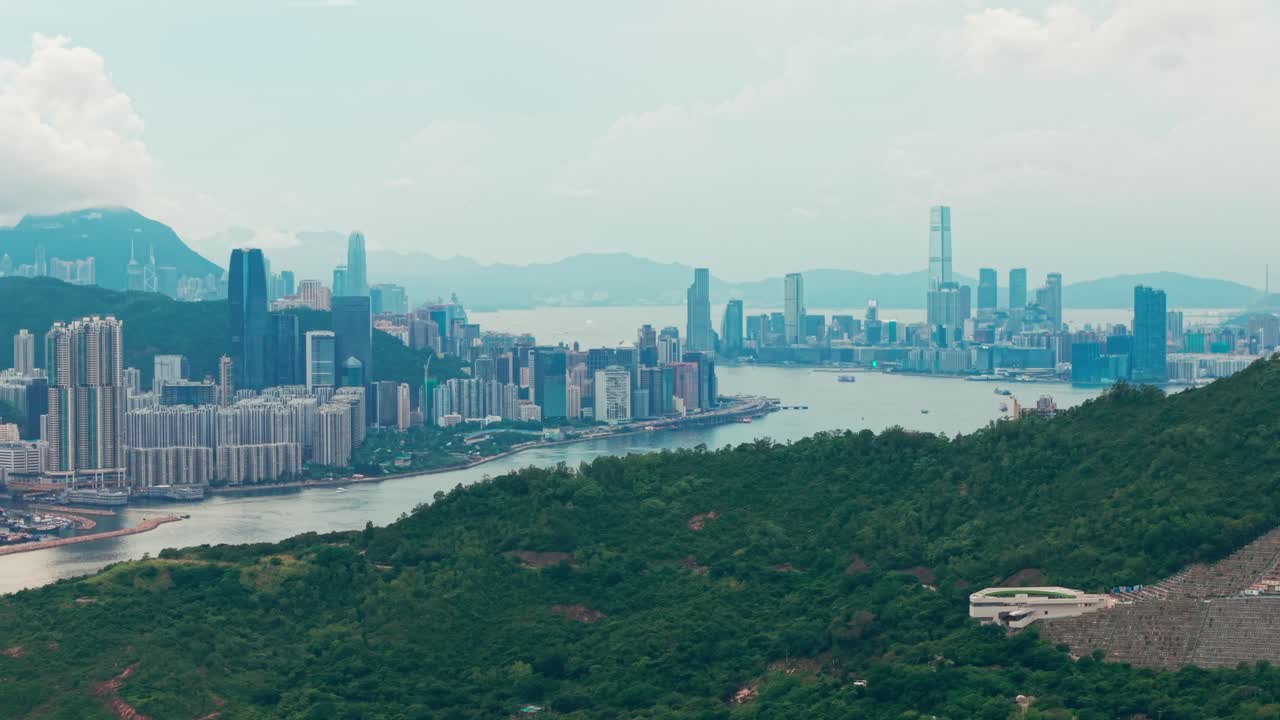 Drone shot of Hong Kong island and Kowloon near Victoria Harbour during a cloudy sunset day as the camera descends