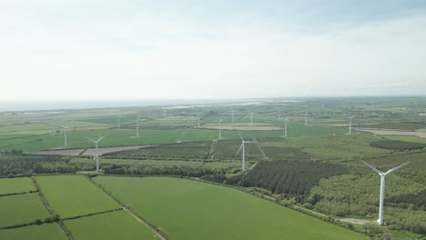 rotating wind turbines towering over greenery fields in wexford county, ireland