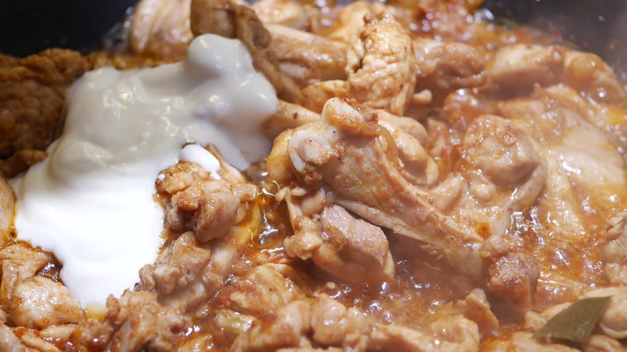 Pezzi di pollo in cottura con salsa cremosa in una padella calda