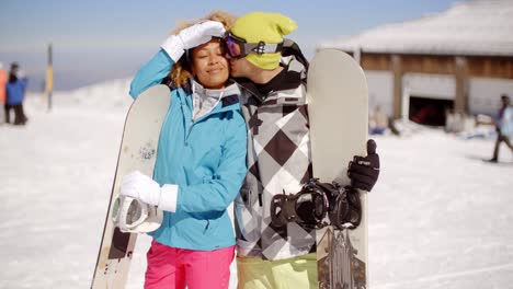 affectionate young couple posing with snowboards