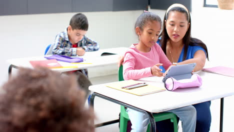 in school, teacher helping student with tablet in classroom, focusing on learning