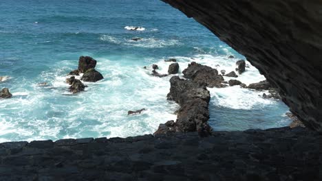 Olas-Con-Espuma-Corren-Sobre-La-Roca-En-La-Costa,-El-Agua-Se-Rompe-En-Salpicaduras-Y-Espuma-Blanca