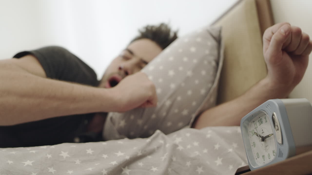 hombre soñoliento despertando por la mañana. hombre relajado mirando el despertador.